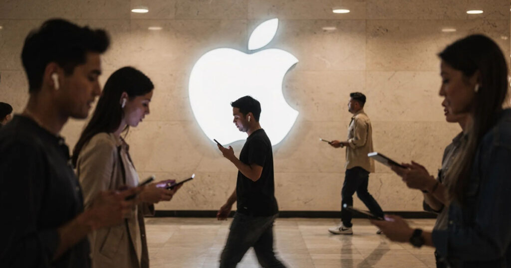 People walking past a large Apple logo while using iPhones and other devices.