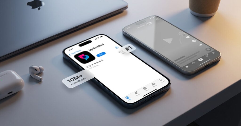 iPhone displaying the UpScrolled app ranked #1 on the App Store with 10M+ downloads badge, placed on a desk beside AirPods and a MacBook.