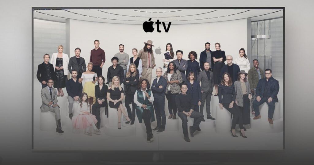 Group portrait of Apple TV creative professionals standing and seated in a modern studio space beneath the Apple TV logo