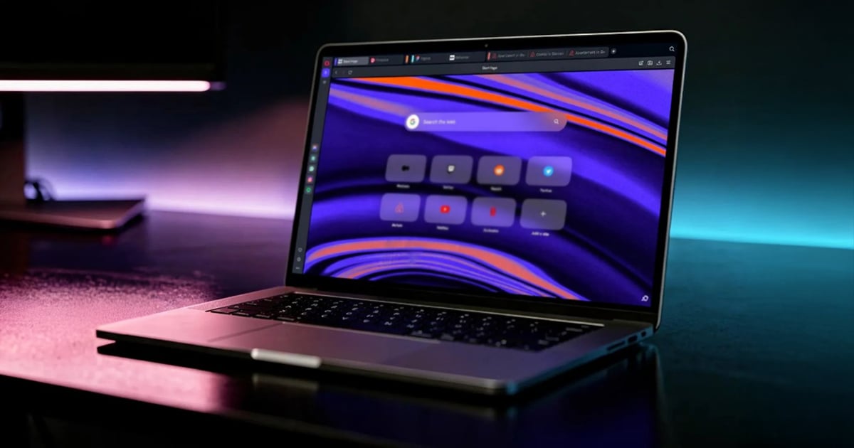 Laptop on a dark desk displaying the Opera One browser start page with color-coded Tab Islands in the tab bar, a search field, and shortcut tiles over a purple and orange wave wallpaper.