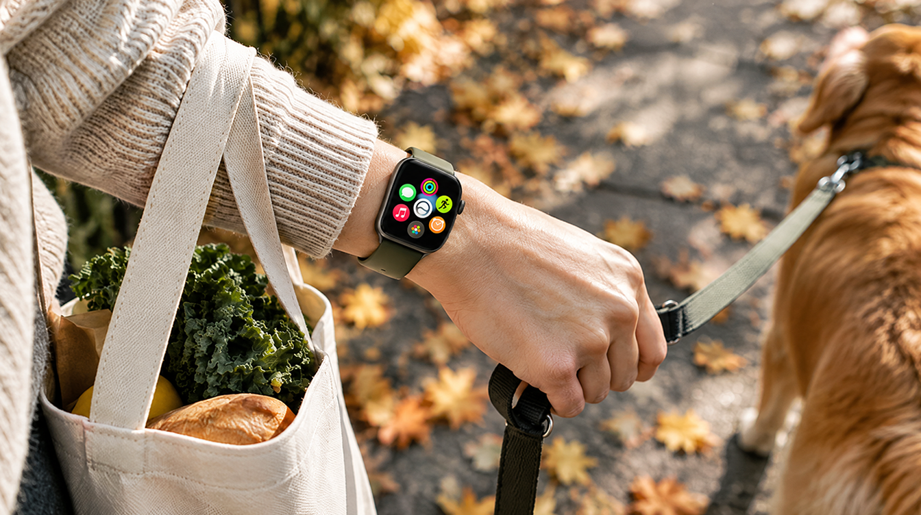 Smartwatch on a wrist holding a dog leash on an autumn sidewalk, where Apple Watch vibration strength matters